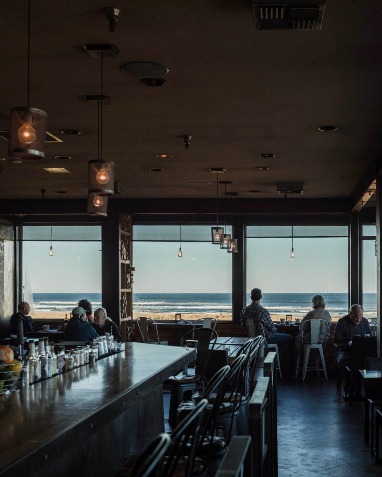People sitting at a bar with a view of the ocean